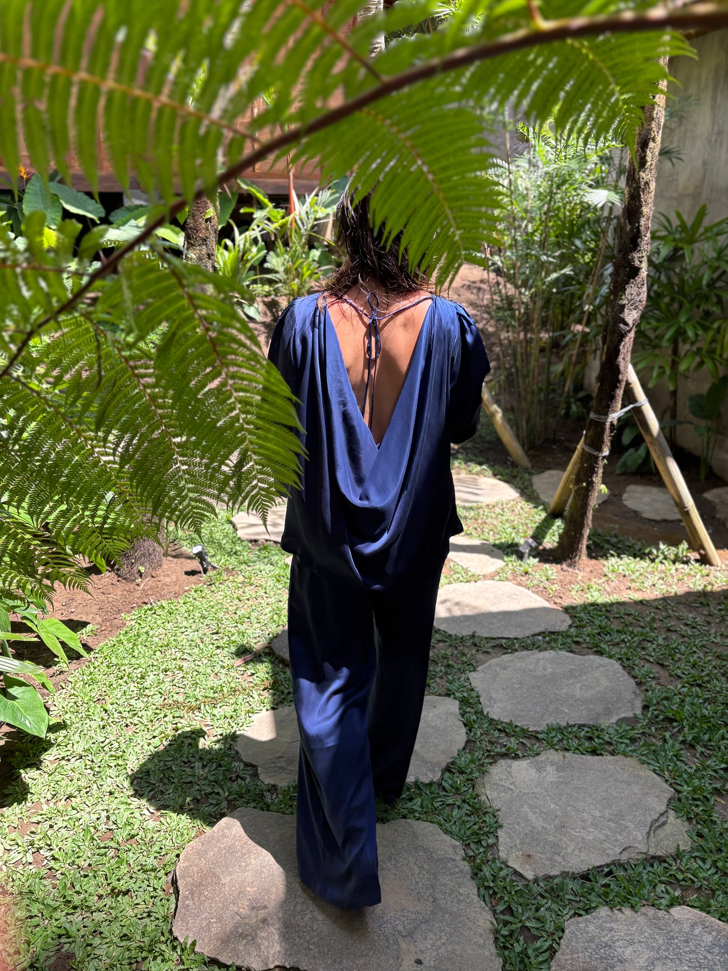 Person wearing a blue dress with an open back standing in a garden.