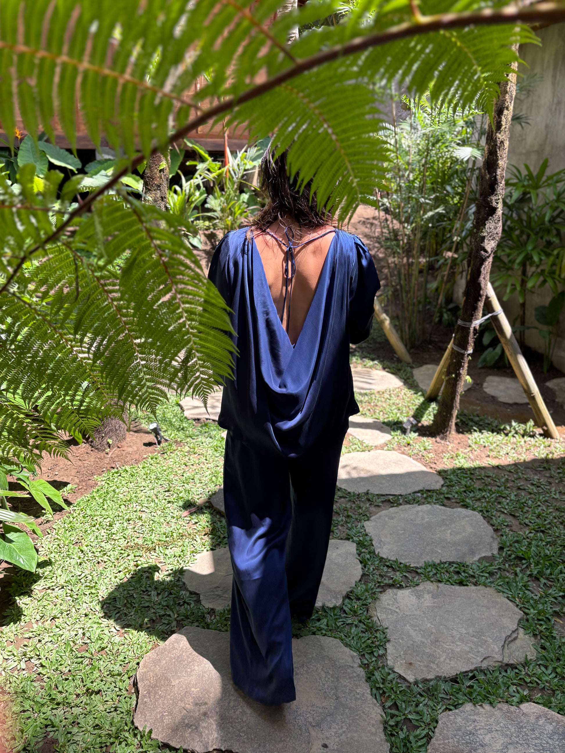 Person wearing a blue dress with an open back standing in a garden.