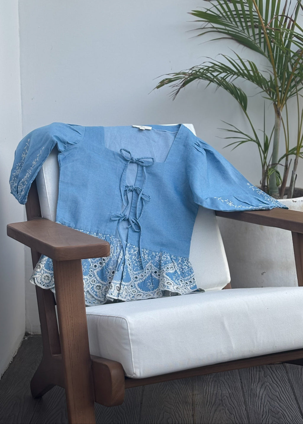 Muse denim blouse with white embroidery, puffy sleeves, and bow-tie details