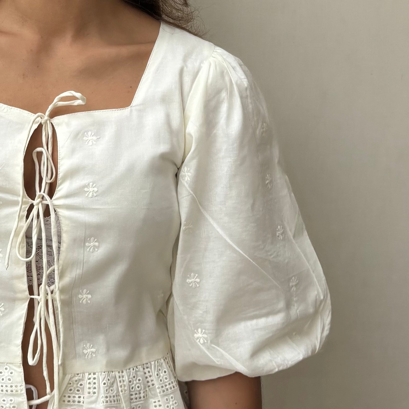 Cotton blouse with subtle chikankari embroidery, puff sleeves, and bow-tie neckline. Handcrafted in small batches by artisans in India for effortless slow fashion.