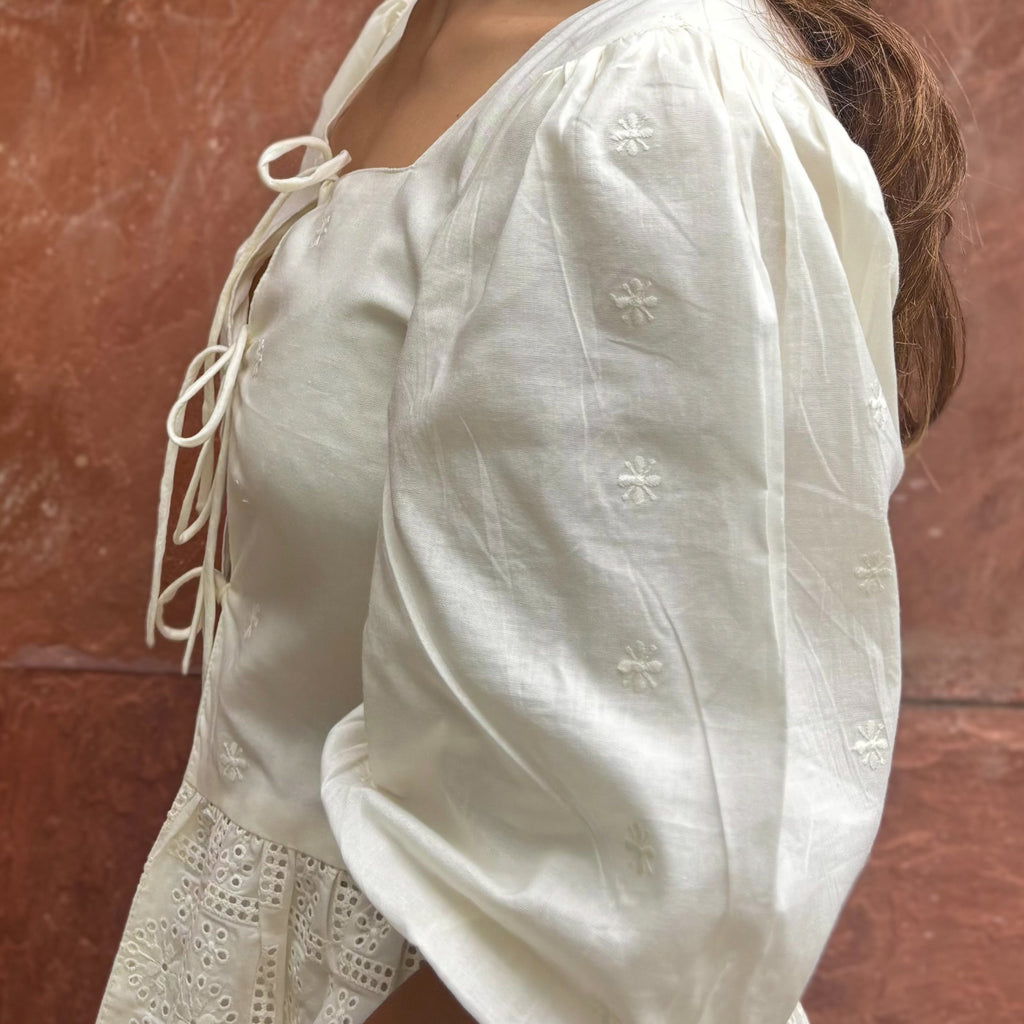 Cotton blouse with subtle chikankari embroidery, puff sleeves, and bow-tie neckline. Handcrafted in small batches by artisans in India for effortless slow fashion.